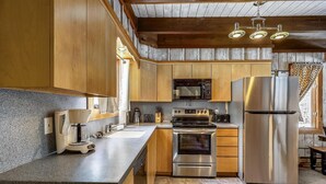 Una cocina con armarios de madera, electrodomésticos de acero inoxidable, encimera de granito y una ventana con cortinas.