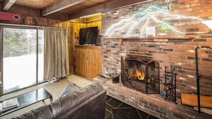 Una habitación acogedora con chimenea de ladrillo, sofá de cuero y televisor.