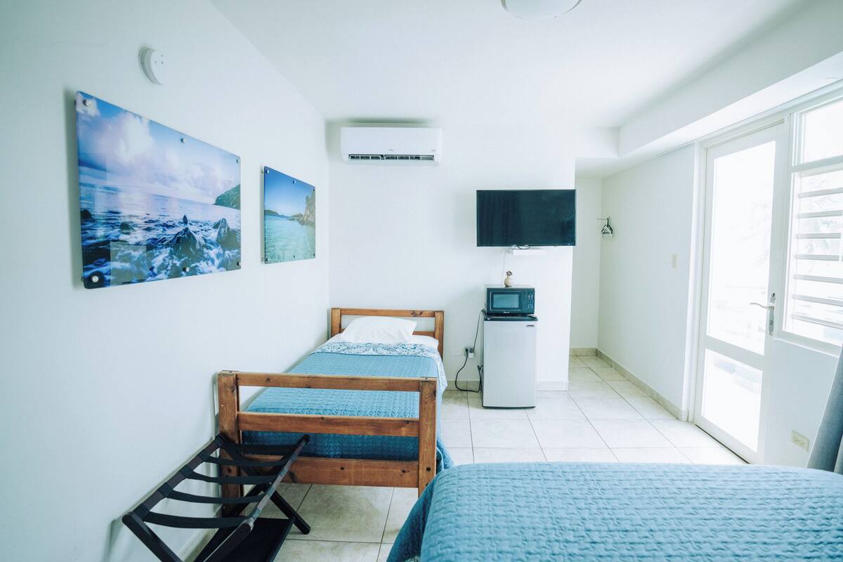 Een slaapkamer met een bed, een bureau, een televisie en een raam.