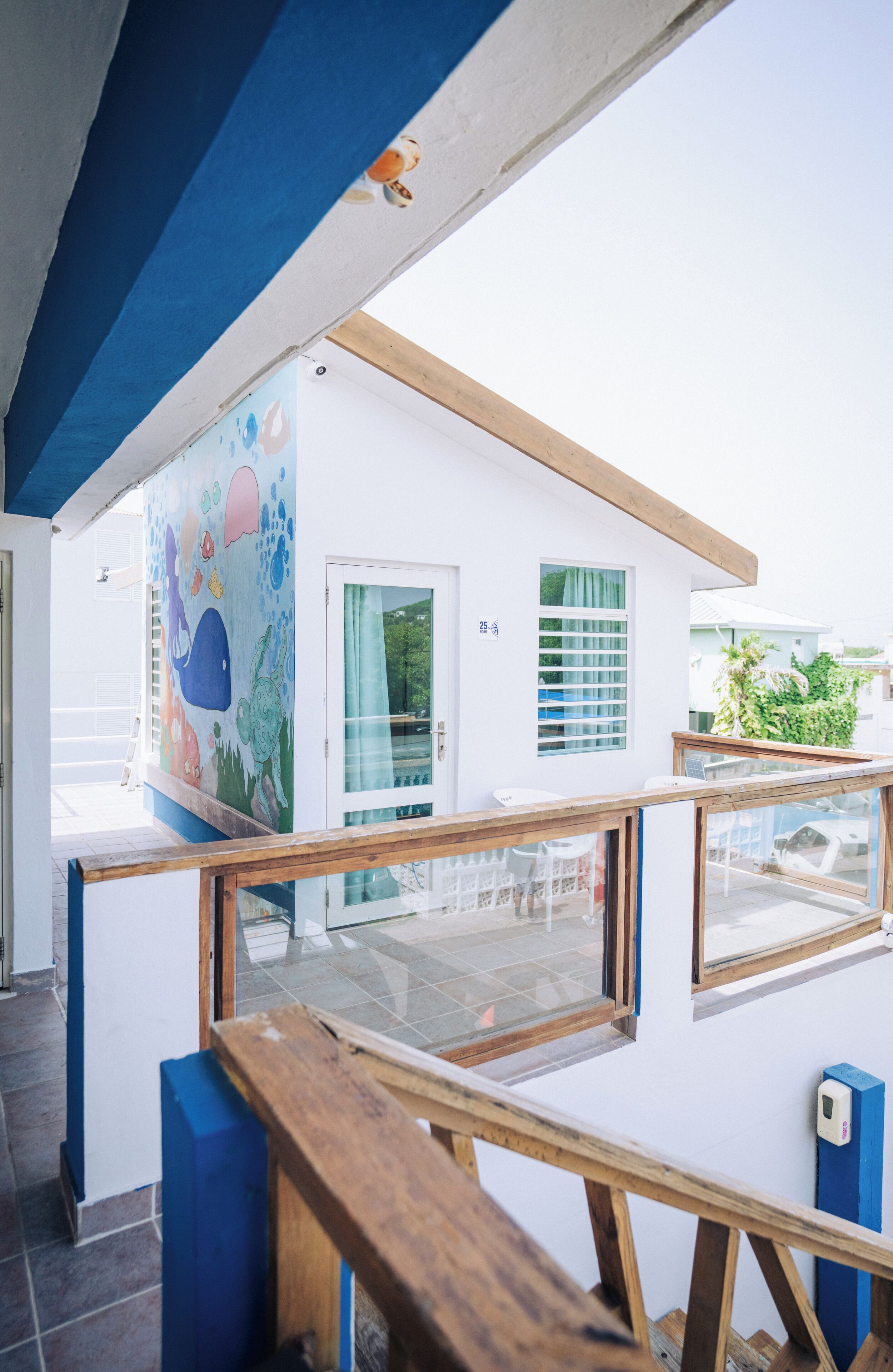 Un edificio moderno con un mural colorido, una terraza de madera y una puerta de cristal.