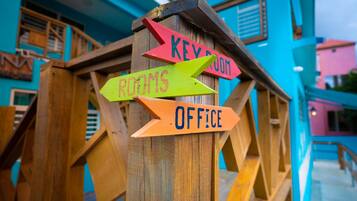 Un cartel de madera con flechas direccionales indicando 'Key Room', 'Rooms' y 'Office'.
