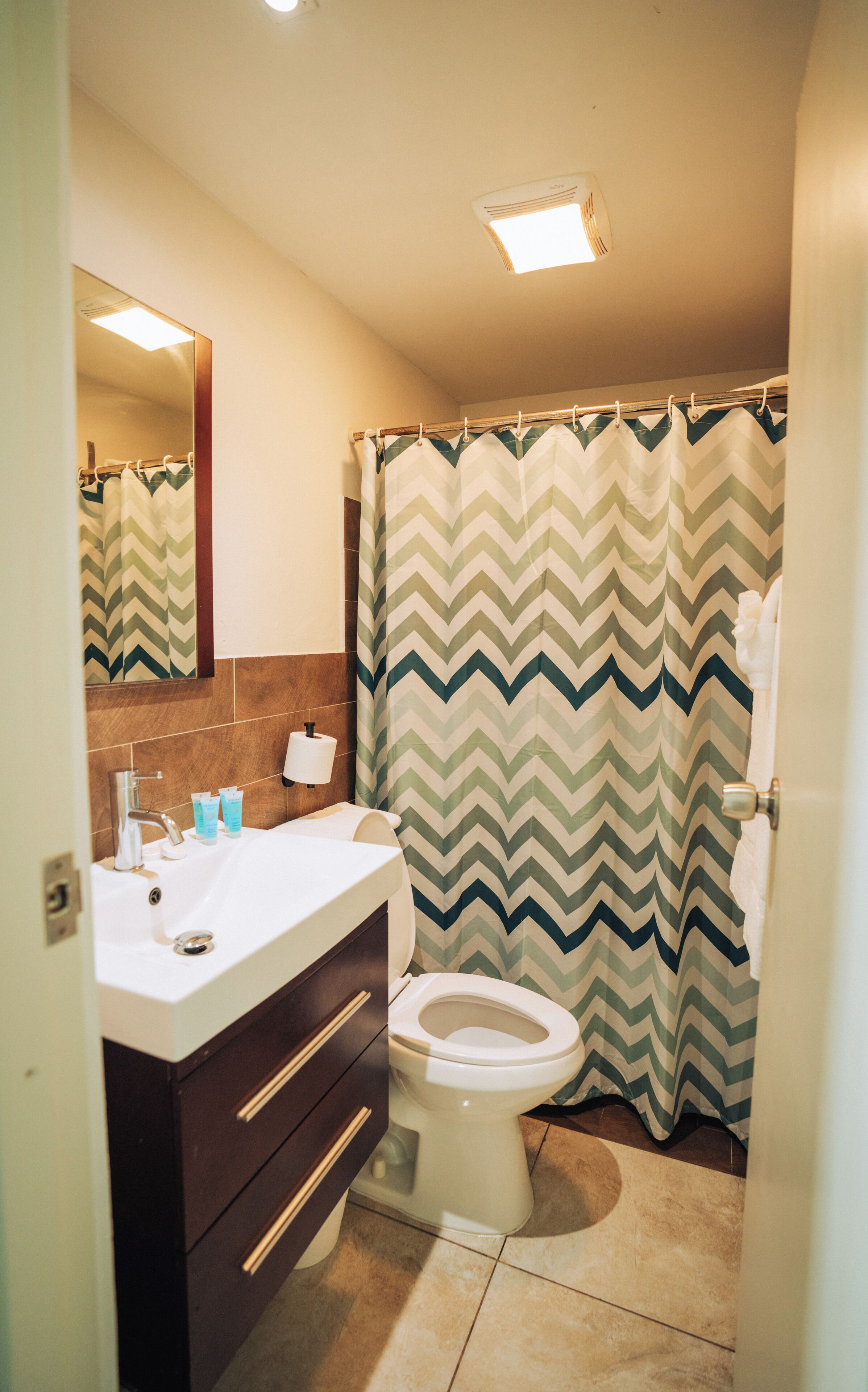 A bathroom with a toilet, sink, and mirror.