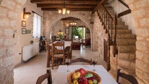 Tunnelmallinen ruokailutila, jossa on kiviseinät, puiset huonekalut ja portaikko.