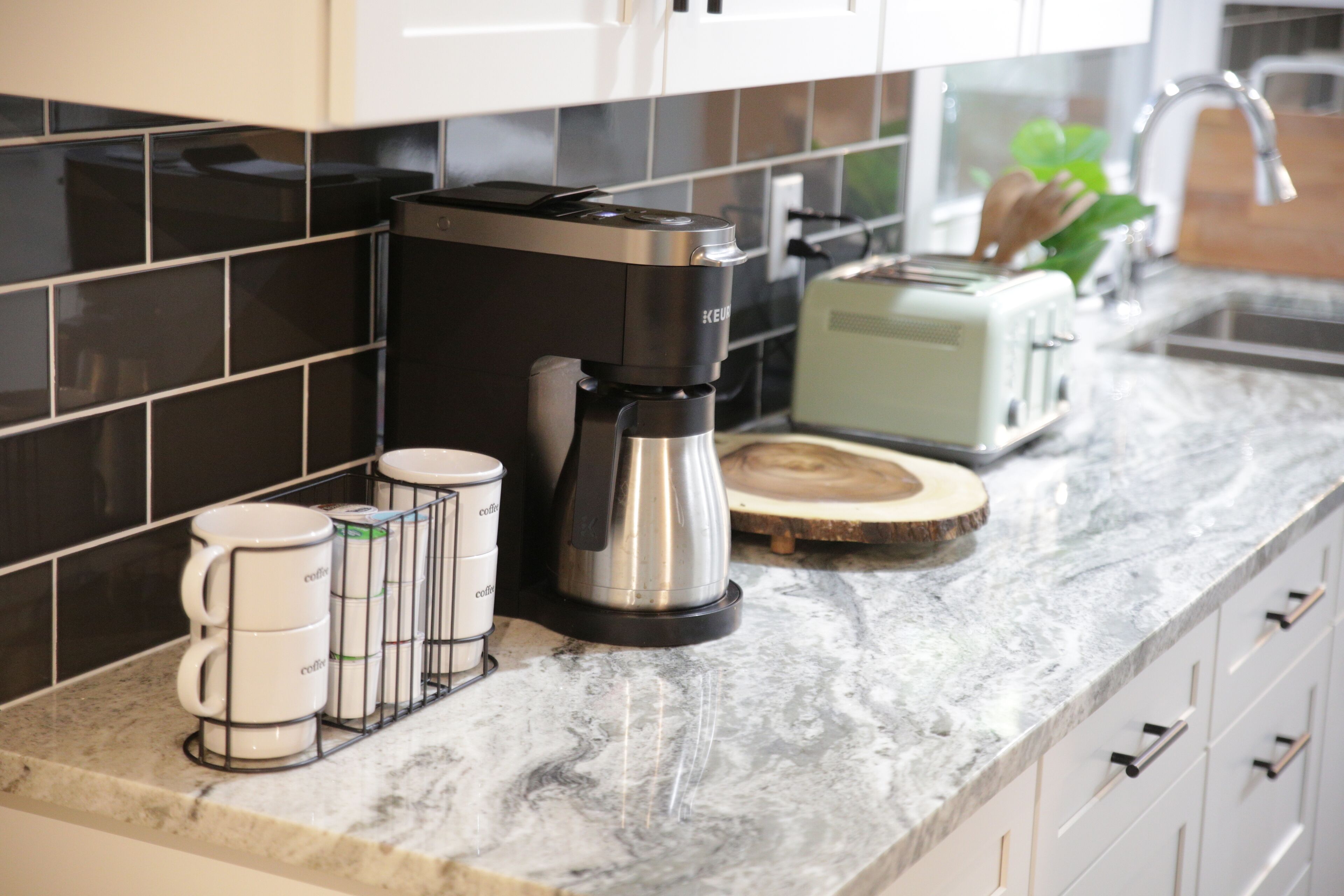 A kitchen with a coffee maker, a toaster, and a coffee mug rack.