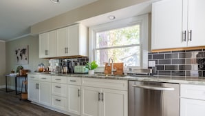 Una cocina moderna con armarios blancos, electrodomésticos de acero inoxidable y un amplio ventanal que proporciona luz natural.