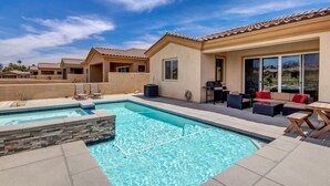 A residential pool area with a clear blue pool, stone-lined edges, and outdoor furniture. - Brand New Desert Princess Villa with Private Pool, Spa and View (Cathedral City)