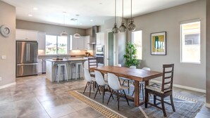 A modern kitchen with a central island, stainless steel appliances, and pendant lighting. - Brand New Desert Princess Villa with Private Pool, Spa and View (Cathedral City)