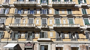 A multi-story building with balconies, storefronts, and a closed shuttered entrance. - Boutique Apartment in Via Roma by Wonderful Italy (Genova)