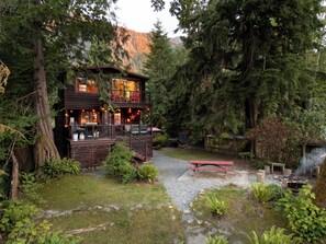 Een chalet met terras, omgeven door dicht bos en een berg op de achtergrond.