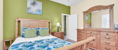 Un dormitorio con cama de madera, mesita de noche, cómoda y ventilador de techo.