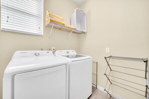 A laundry room with two white washing machines, a drying rack, and a wall-mounted laundry basket.