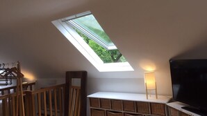 A room with a skylight, a TV, wicker baskets, and a lamp. - Self Contained Coach House (Bromley)