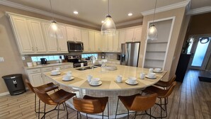 A modern kitchen with a central island, white cabinetry, stainless steel appliances, and pendant lighting.