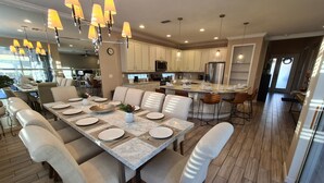 A modern kitchen with white cabinets, a central island with bar stools, and pendant lighting.