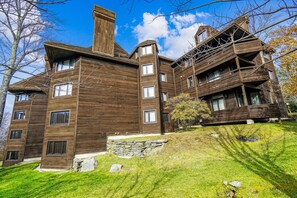 A multi-story wooden building with a stone foundation, large windows, and a sloped roof. - Your adventure starts here Highridge A18 (Killington)