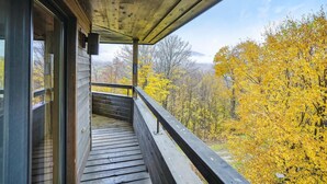 Un balcon en bois offrant une vue sur le feuillage automnal.