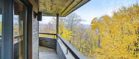 A wooden balcony with a view of autumn foliage.