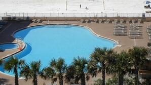 A pool adjacent to a beach with lounge chairs and umbrellas. - Gulf Front PH •Free Chairs• Best Views in PCB (Panama City Beach)