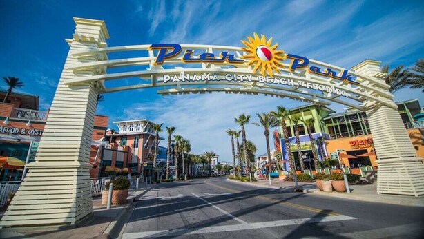 L'entrée du quai 70, à Panama City Beach, avec un ciel dégagé et des palmiers.