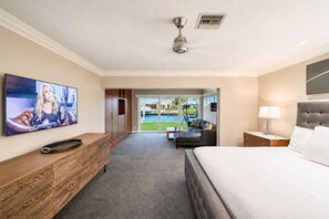 A hotel room with a bed, a TV, a desk, and a view of a pool. - Luxurious, Modern Fort Lauderdale House with Waterfront Pool & Spa (Fort Lauderdale)