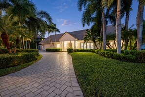 A residential property with a paved driveway, well-maintained lawn, and palm trees. - Luxurious, Modern Fort Lauderdale House with Waterfront Pool & Spa (Fort Lauderdale)