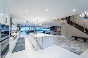A modern kitchen with a marble island, built-in appliances, and a view to the outside. - Luxurious, Modern Fort Lauderdale House with Waterfront Pool & Spa (Fort Lauderdale)