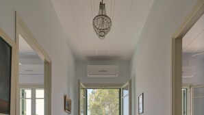 A hallway with wooden flooring, a chandelier, and a view through a glass door to an outdoor area.