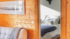 A wooden-paneled room with a bed, a wall-mounted deer head decoration, and a framed artwork depicting sheep. - La Ménandière - 3 bedrooms (Megève)