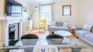 A living room with a fireplace, a sofa, a yellow armchair, and a television. - 3 bedroom accommodation in Mundesley, near North Walsham (Mundesley, near North Walsham)