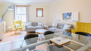 A modern living room with a glass dining table, two sofas, and a yellow armchair. - 3 bedroom accommodation in Mundesley, near North Walsham (Mundesley, near North Walsham)