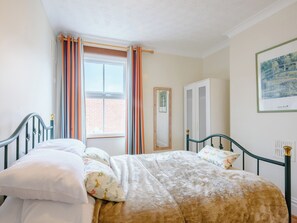 A bedroom with a bed, curtains, a wardrobe, and a framed picture on the wall.