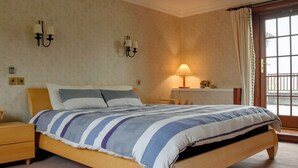 Een slaapkamer met een bed, nachtkastjes, een lamp en een raam met gordijnen.