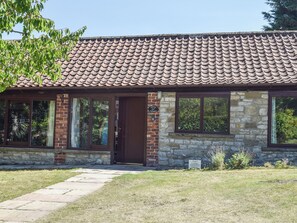 Ein Ferienhaus mit Ziegeldach, Steinmauern und einem Backsteinportal.