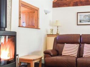 A living room with a fireplace, a wooden cabinet, a leather sofa, and a framed picture on the wall.