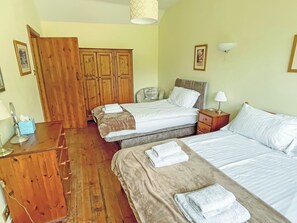 A hotel room with two beds, wooden wardrobe, bedside tables, and a lamp.