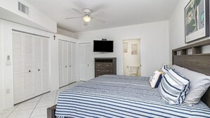 Ein Schlafzimmer mit einem großen Bett, einem Deckenventilator, einem Fernseher und einem Kleiderschrank.