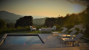 A wooden deck with a swimming pool, lounge chairs, and a table. - Villa PETRU **** with swimming pool, sea view, 10 mn from the beach (Sari-d'Orcino)