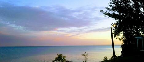 A coastal view with a calm sea, a clear sky, and a street lamp on the right.
