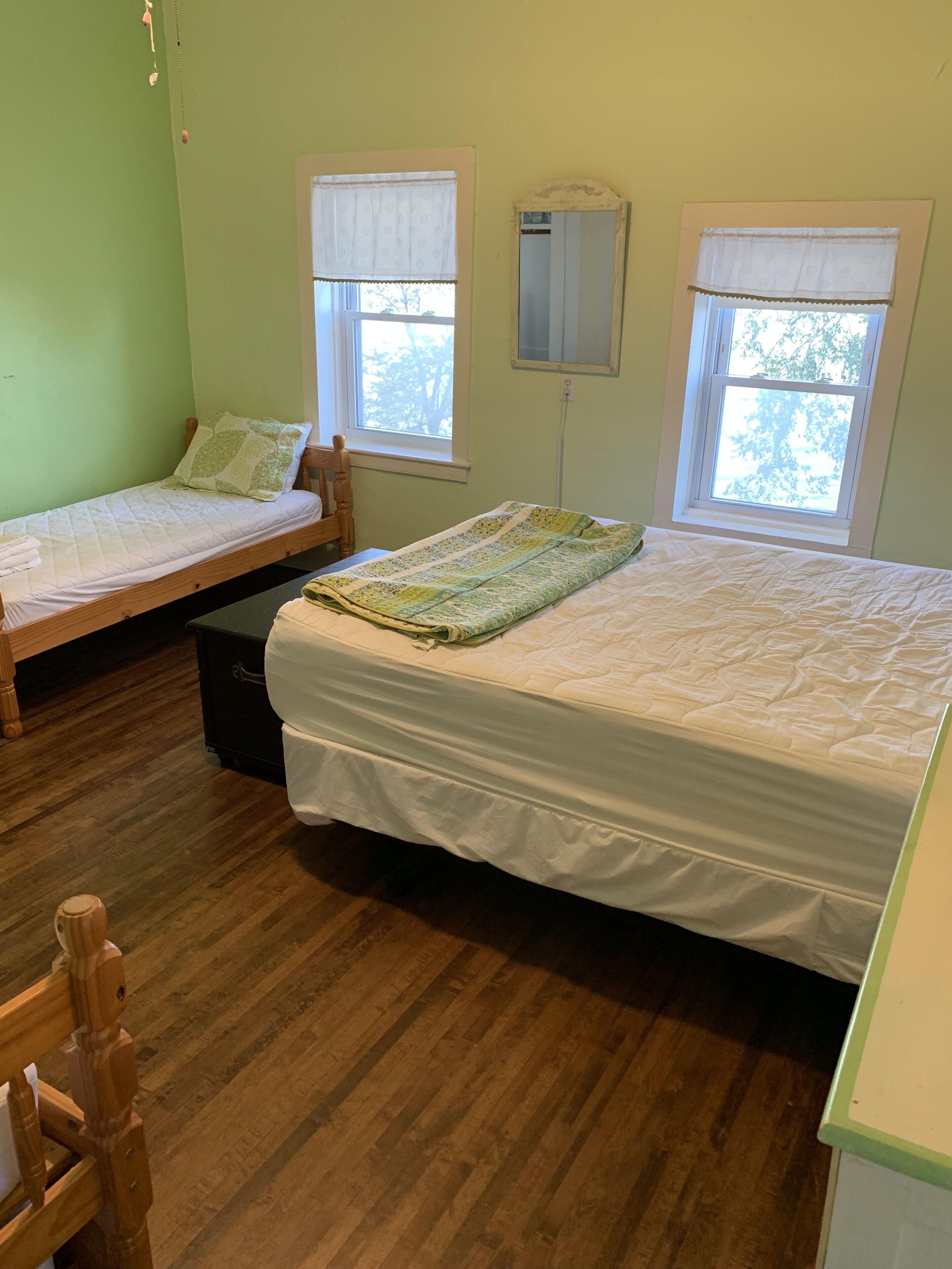 Un dormitorio con dos camas individuales, una silla de madera y una mesita.
