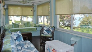 A room with a bed, a chair, and a window overlooking a garden. - Enjoy the View From this Charming Lakefront House in Private Park (Huron)