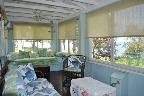 A room with a bed, a chair, and a window overlooking a garden.