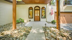 A house with a covered porch, a front door with three arched windows, and an American flag.