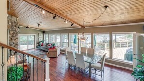 A spacious dining area with a glass table and chairs, a stone wall, and a view of the outdoors.