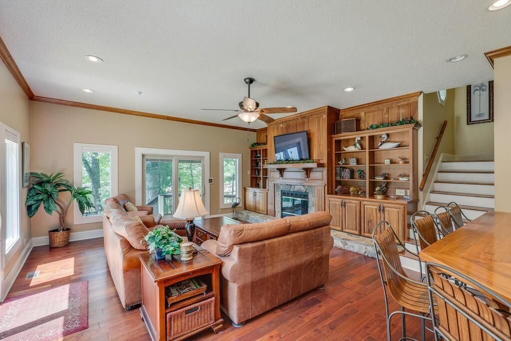 A spacious living room with a fireplace, a dining area with a wooden table and chairs, and a kitchen with wooden cabinets and a TV.