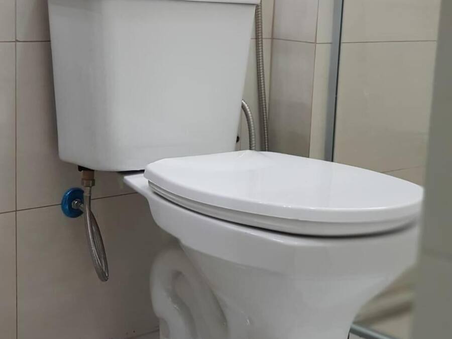Inodoro blanco con descarga por pedal, bidé instalado en la pared y cabezal de ducha.