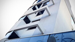 A modern building with a geometric facade and a glass lower section reflecting its surroundings. - Aero Inn Hotel (Uberlandia)