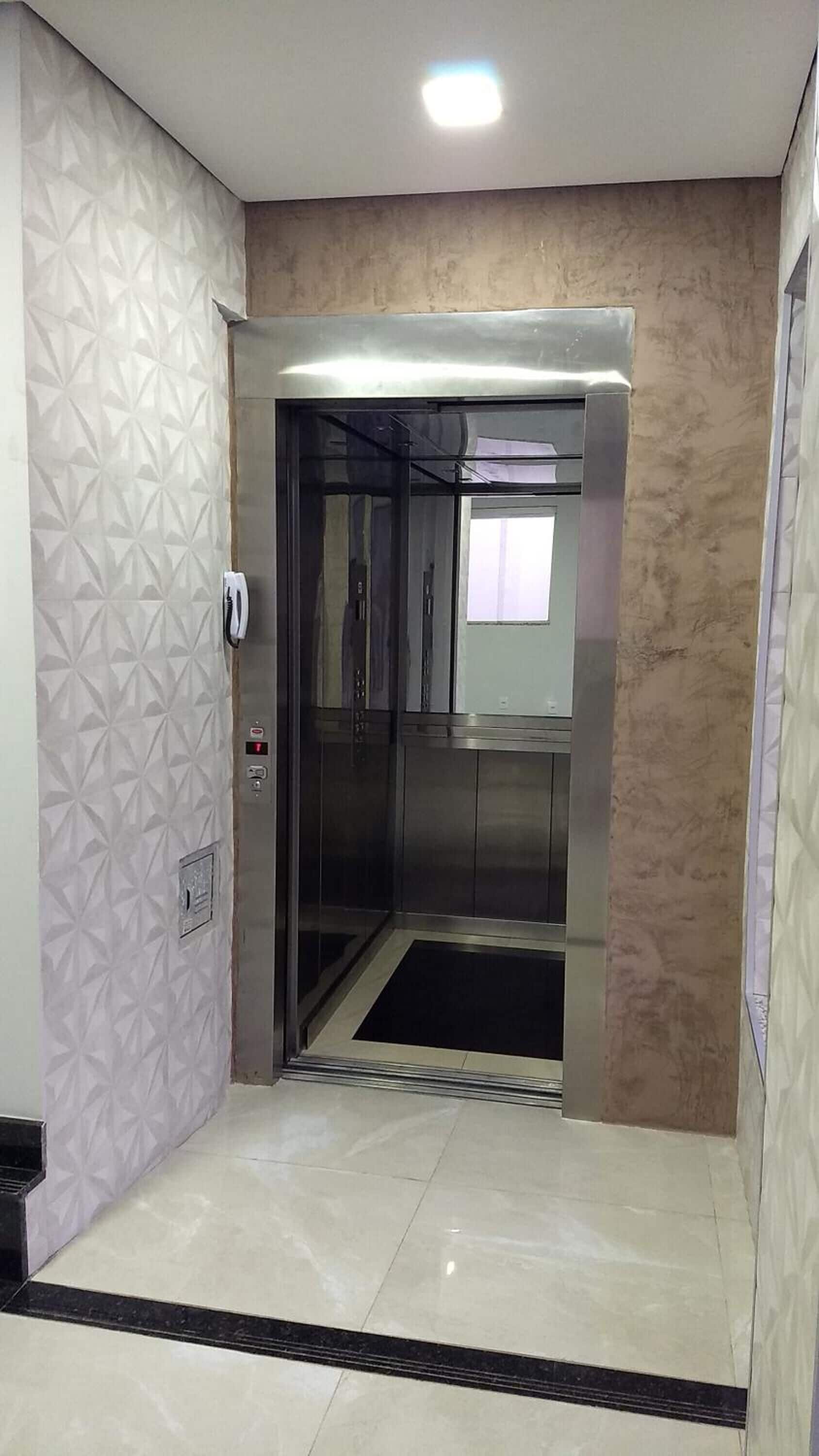 Un ascensor con acabado metálico, un panel de control con botones y una pared con diseño.