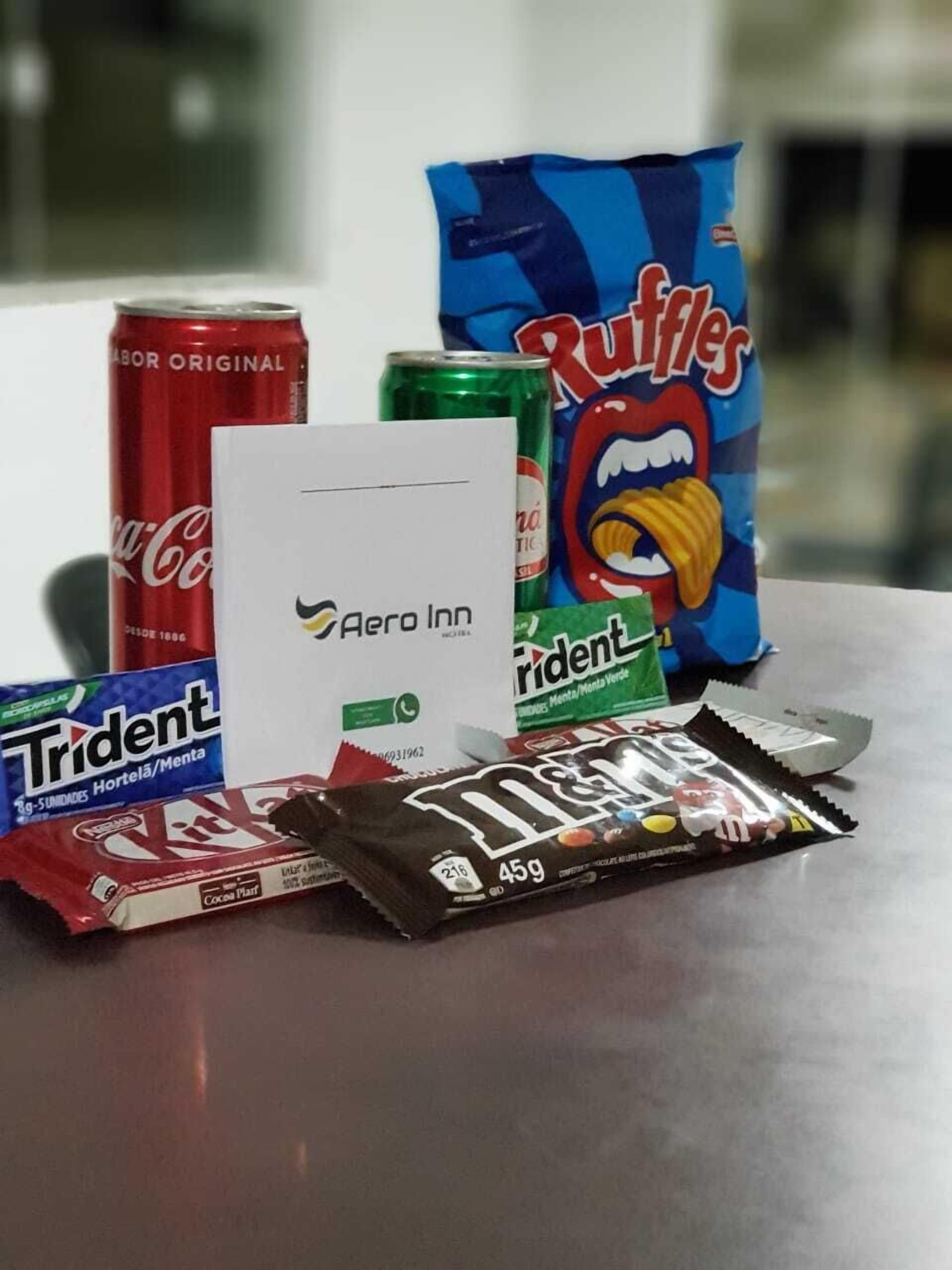 A variety of snacks including a can of Coca-Cola, a bag of Ruffles chips, a package of Trident gum, a pack of M&M's, and a box of Aero Inn branded items.