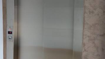 A metallic elevator with a control panel on the left side.