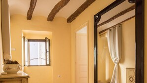 Un pasillo con suelo de baldosas, techo de madera y un espejo grande en la pared.
